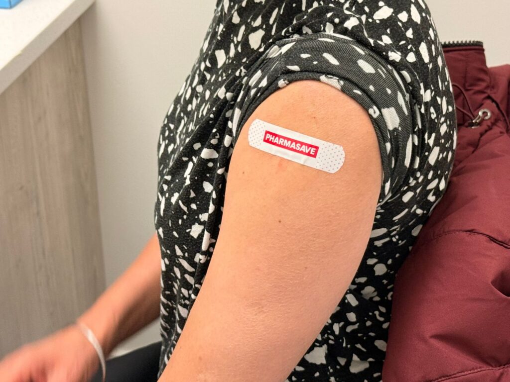 Close-up of an arm with a Pharmasave bandage after vaccination. Ideal for health-related topics.